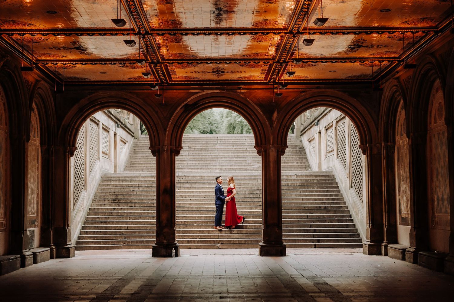 Dramatic engagement photo in historic archway with stone staircase and ornate architecture.