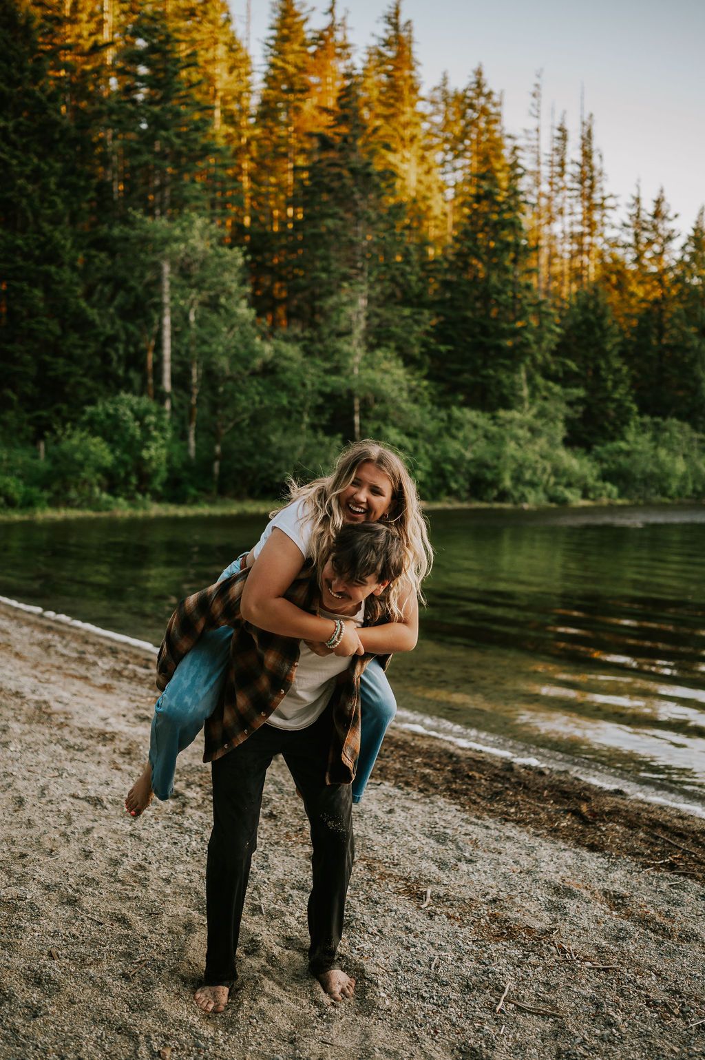 Couple piggybacking by lake and laughing in Strathcona Vancouver Island. Photography by Photographer Soulfull Photographs