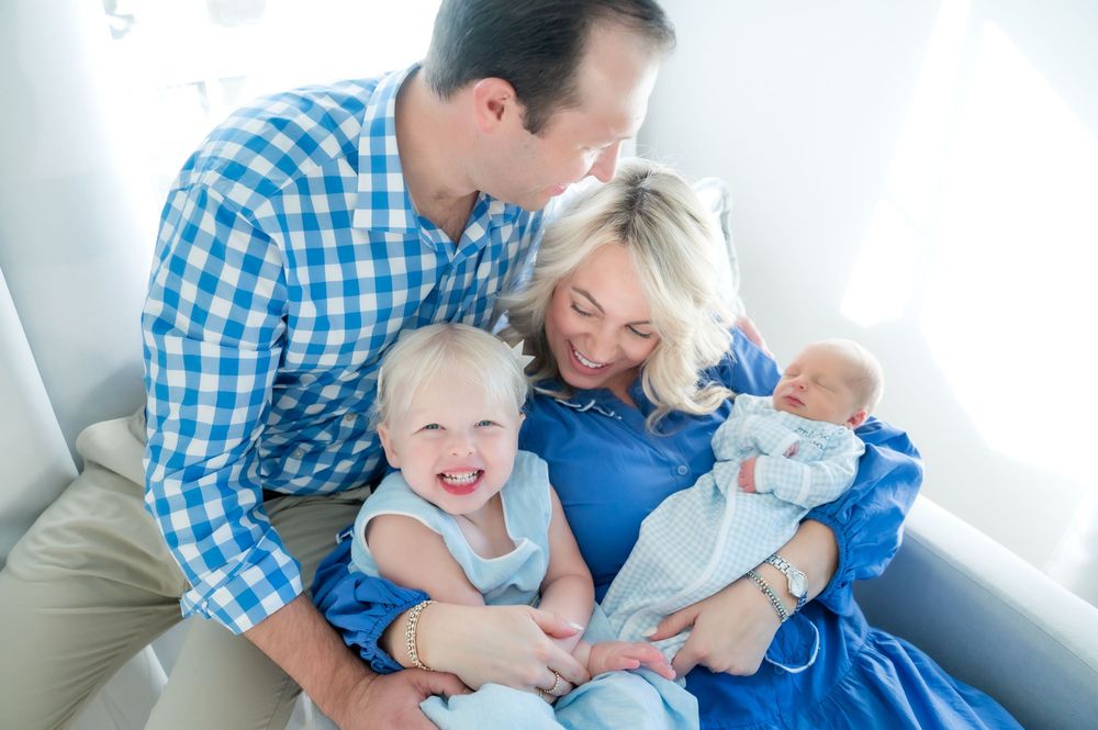 A family in coordinating blue outfits relaxes together and shares joyful laughter on a couch.