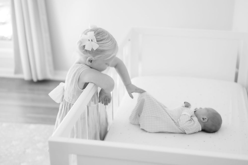 A black and white photograph shows a parent lifting an infant during a diaper change on a changing table.