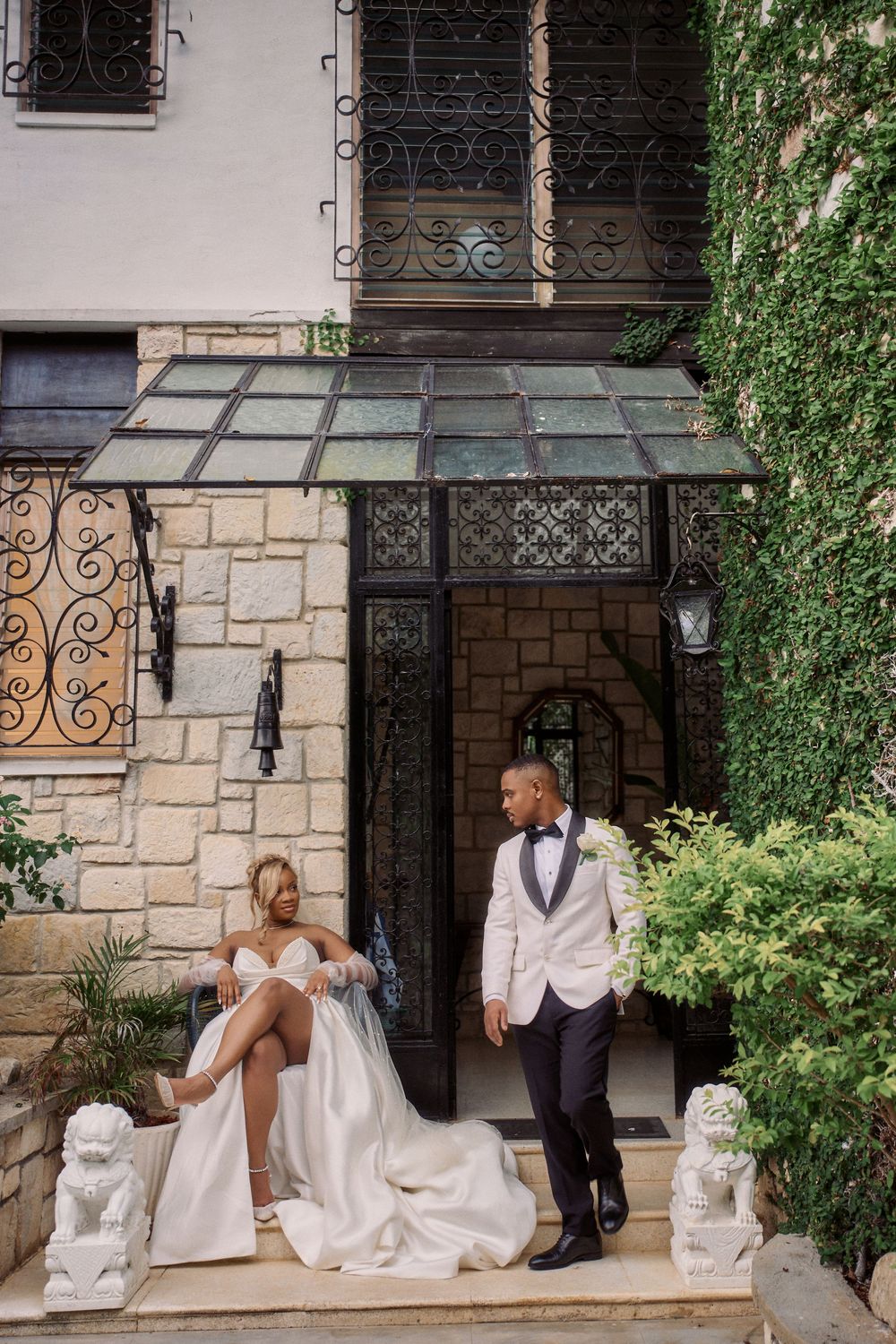 Stone building entrance with decorative railings and steps features a wedding couple in formal Jamaica Wedding Photographer