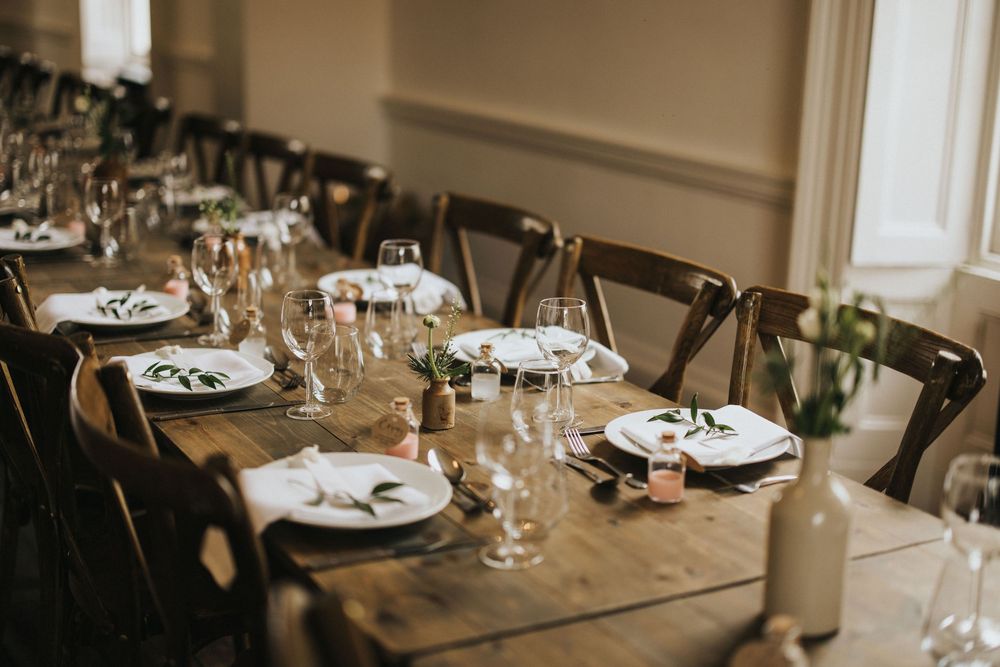 A wedding reception venue is set with elegant place settings and natural light streaming through large windows at Aswarby Rectory.