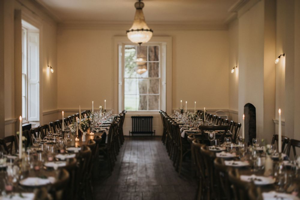 Elegant dining room with long dark tables set for formal dinner featuring candlesticks and vintage pendant lighting at Aswarby Rectory.
