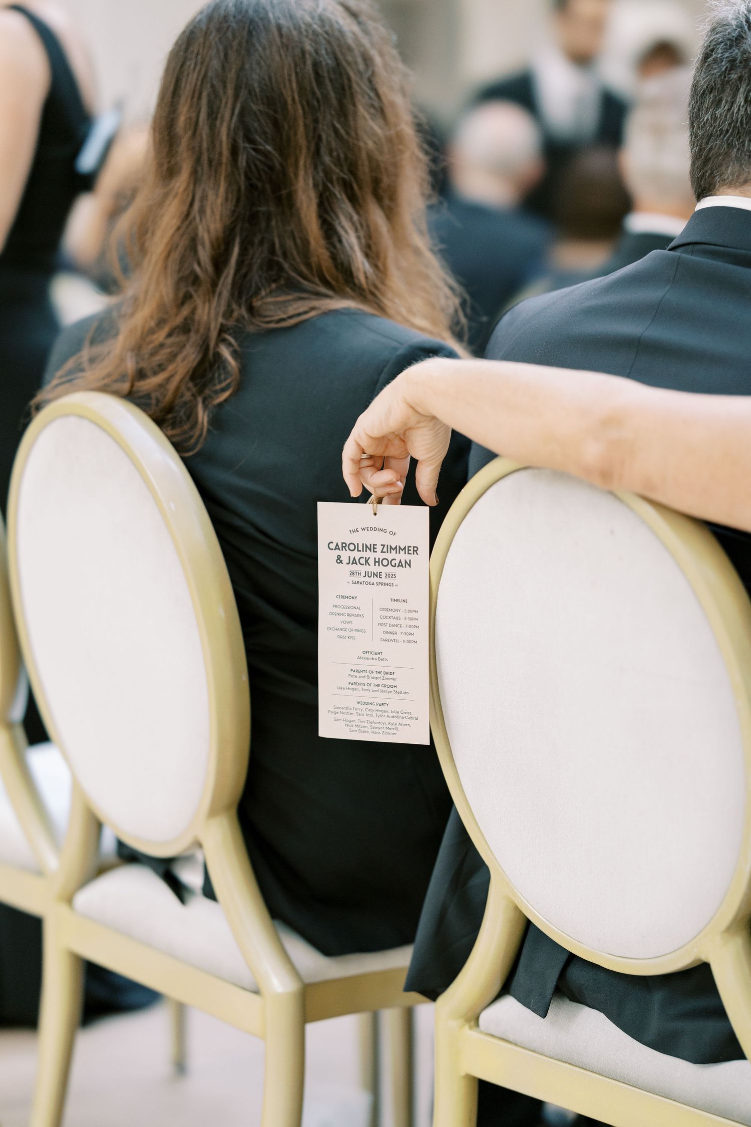 Wedding ceremony program brochures placed on white French style chairs in a row at an elegant venue.
