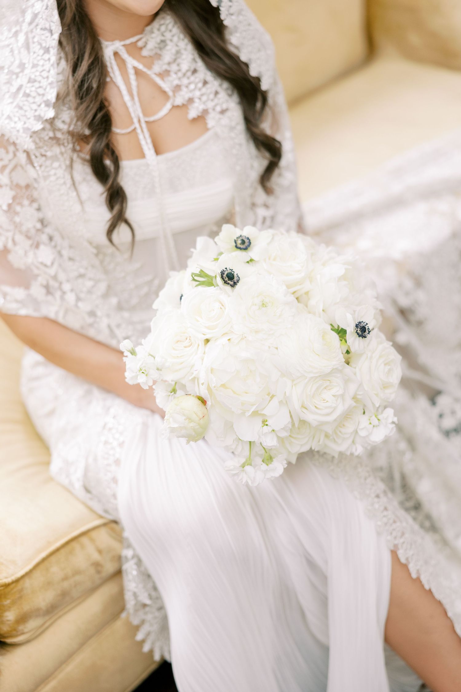 Elegant white bridal bouquet with roses and lace details on a lace wedding dress.