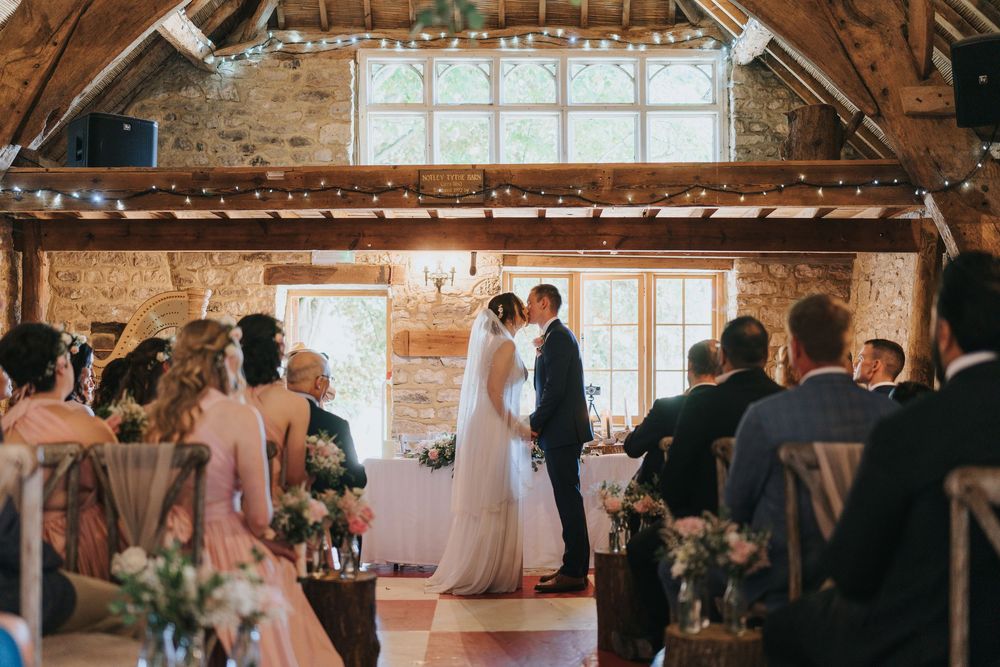 Wedding reception party in a rustic barn venue with exposed wooden beams and natural lighting.