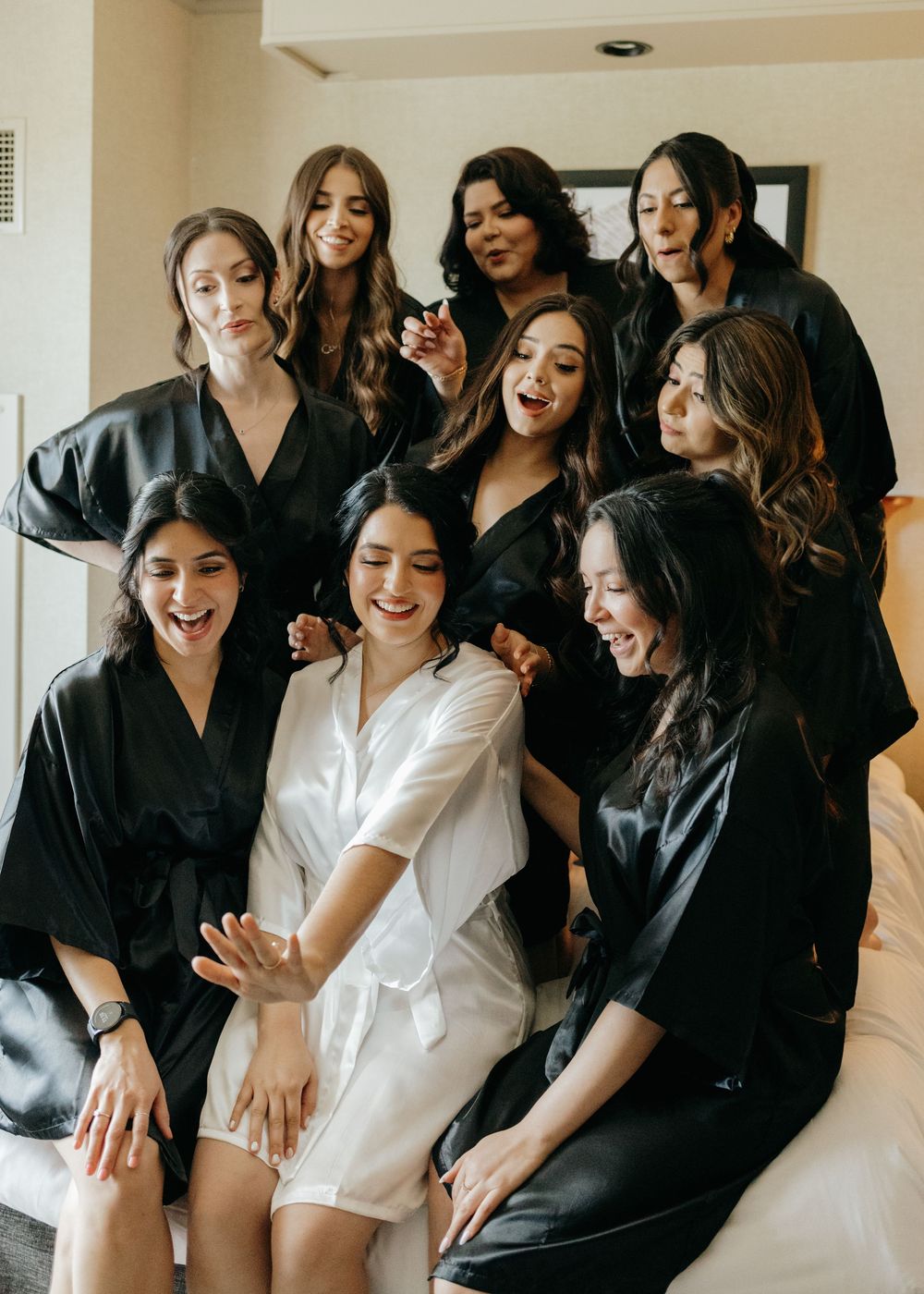 Wedding party wearing black and white robes laughing and having fun during pre-ceremony preparations.
