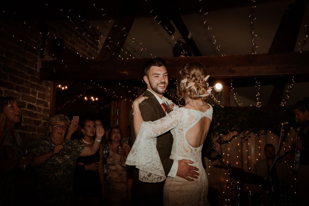 A couple dances together in an intimate rustic venue with twinkling lights at Hall Farm - image captured by Grimsby photographers.