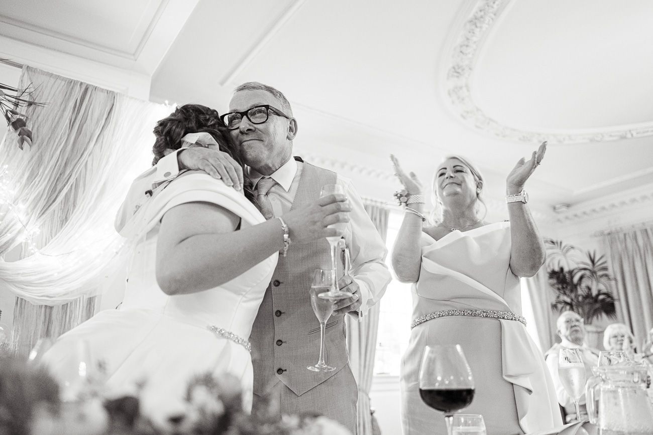 Black and white collage of wedding celebration moments with wine glasses, dancing, and laughter at formal reception.