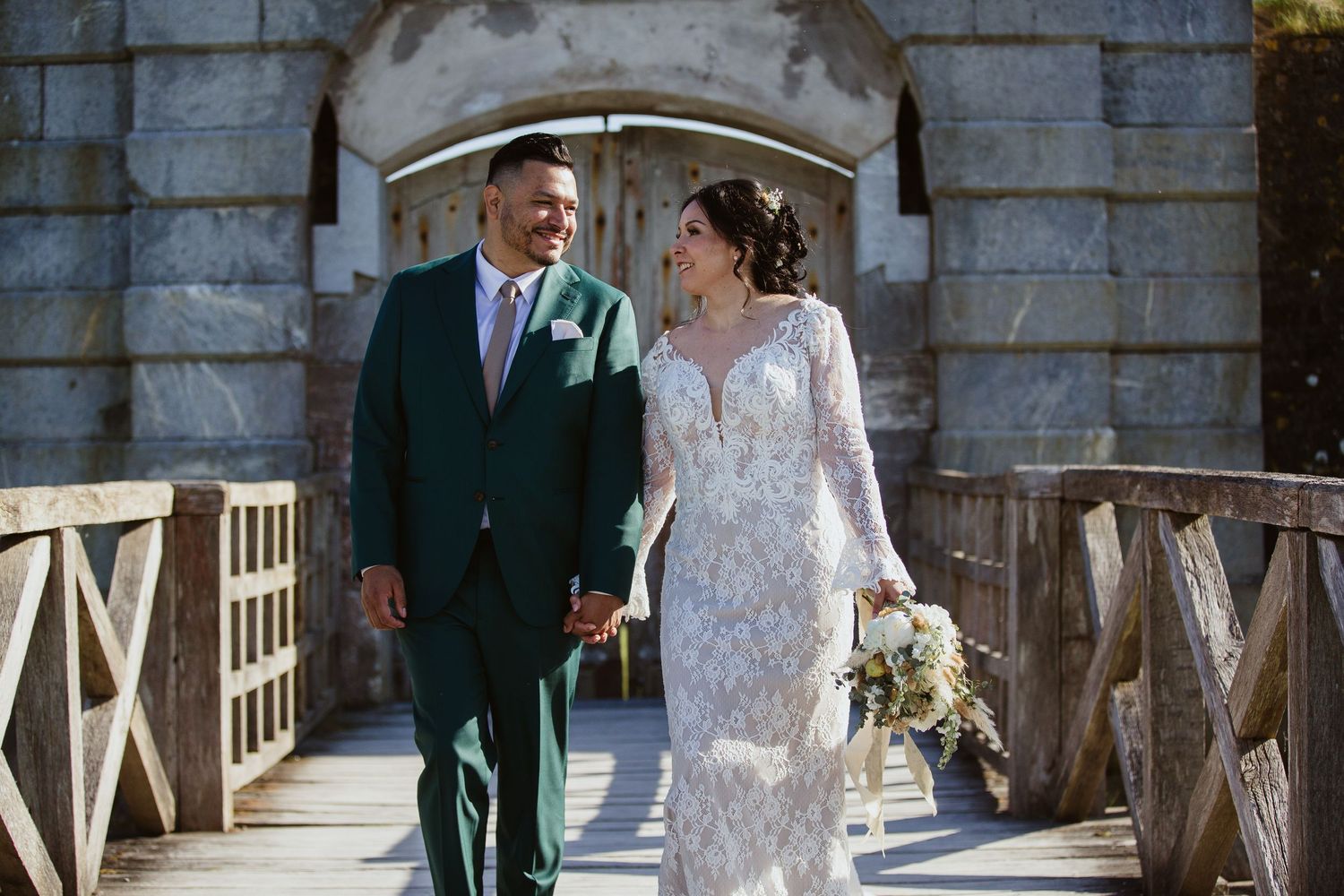Newlywed couple shares a romantic moment under an arched stone entryway at their outdoor castle wedding.