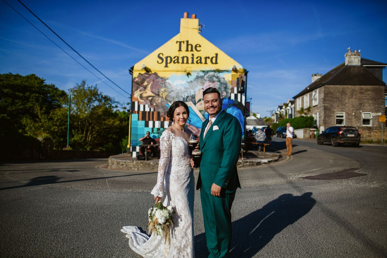 A wedding couple poses in front of The Spaniard pub with its distinctive yellow facade.