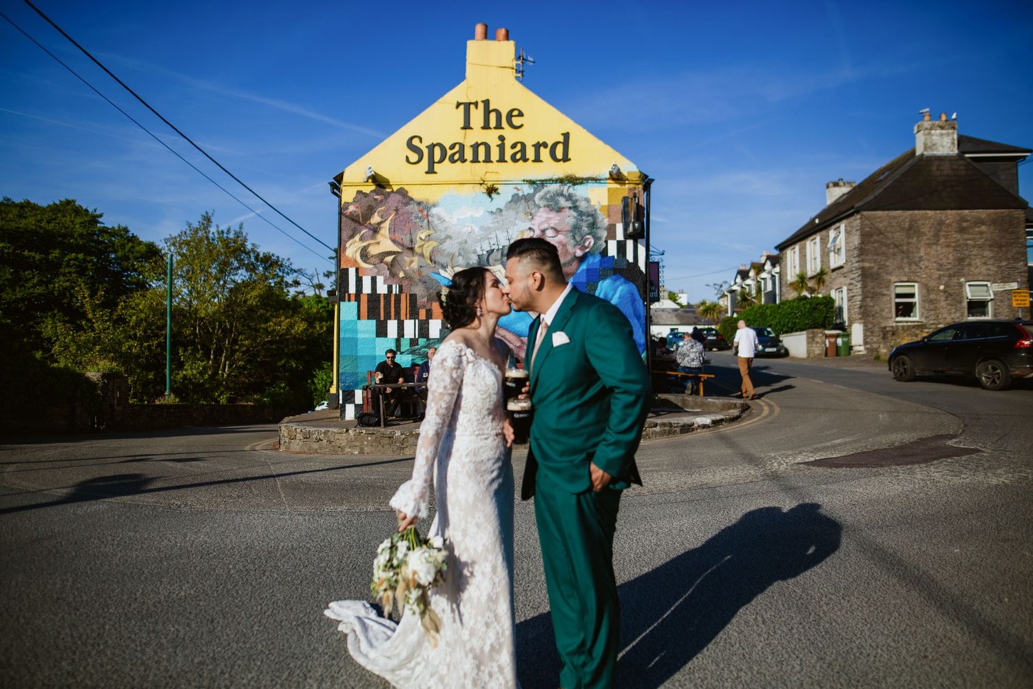 A wedding portrait captured in front of a yellow pub building called The Spaniard on a sunny day.