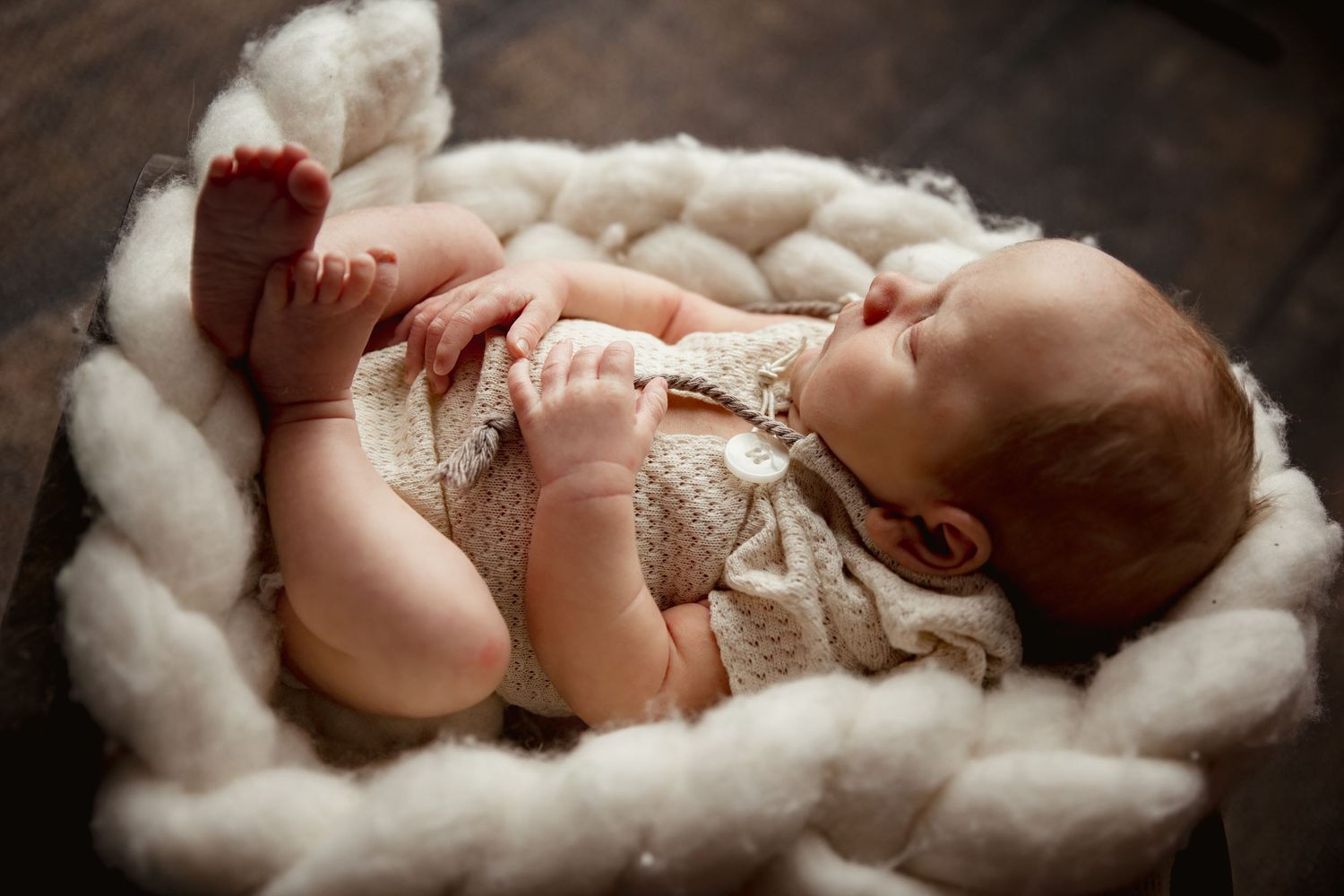 Baby resting peacefully in plush white fur blanket during professional newborn photography session.