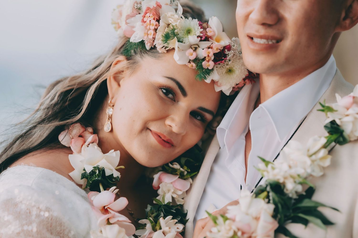 A romantic wedding scene with pink and white florals framing a tender close-up moment.