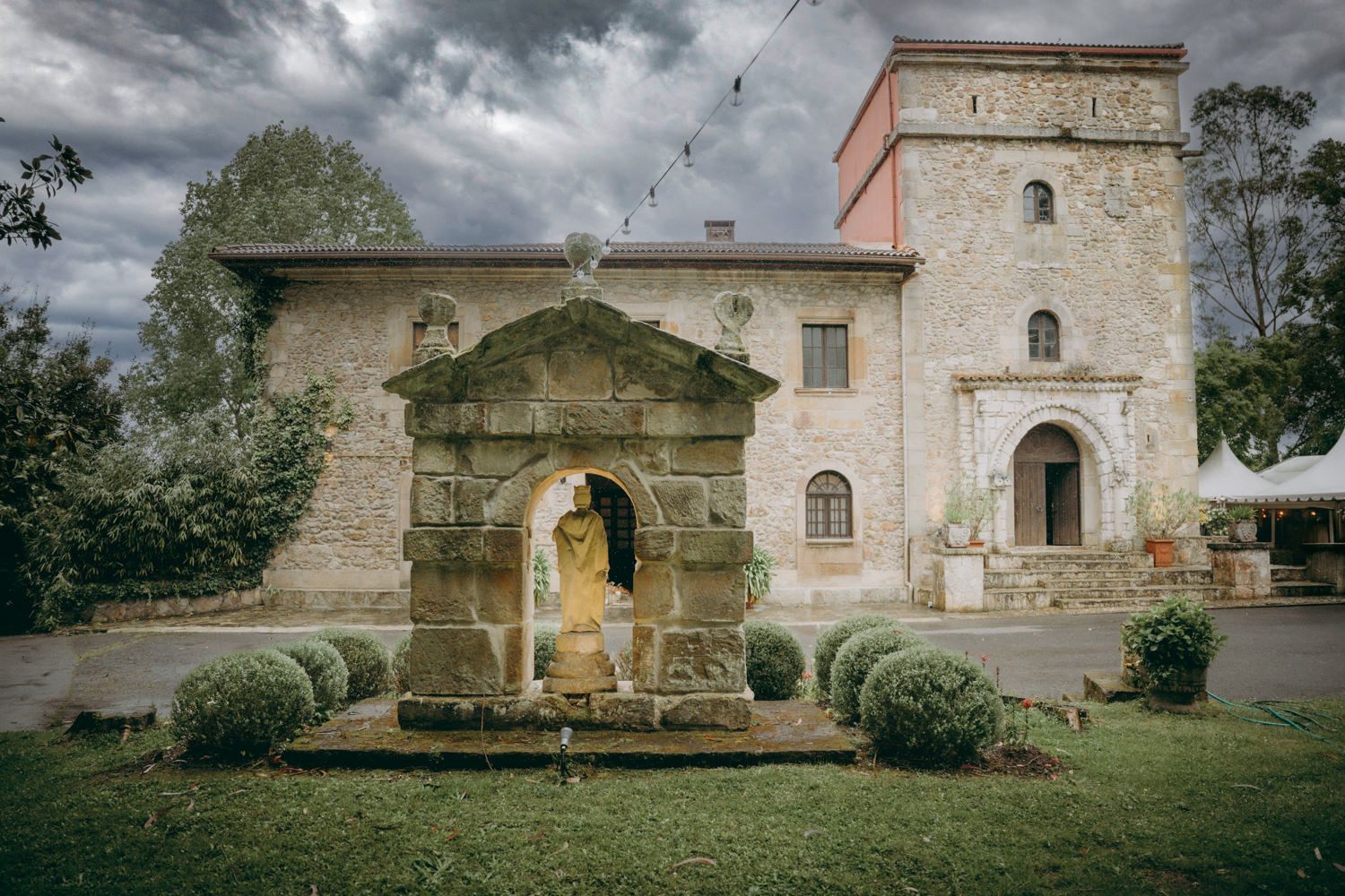 Palacio de Villabona, con fuente ornamentada y jardín formal bajo un espectacular cielo y nublado en un día de boda en Asturias.