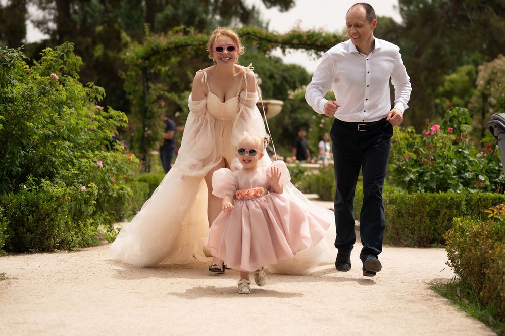 A family walking together through a blooming garden path on a sunny day.
