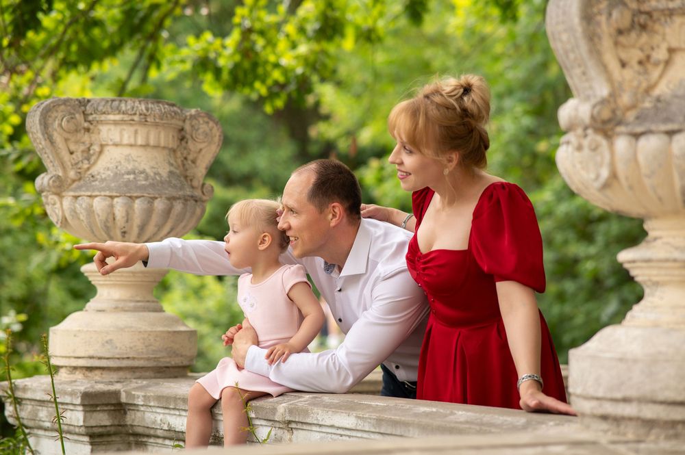 A family moment shared on a decorative stone balustrade surrounded by lush summer greenery.