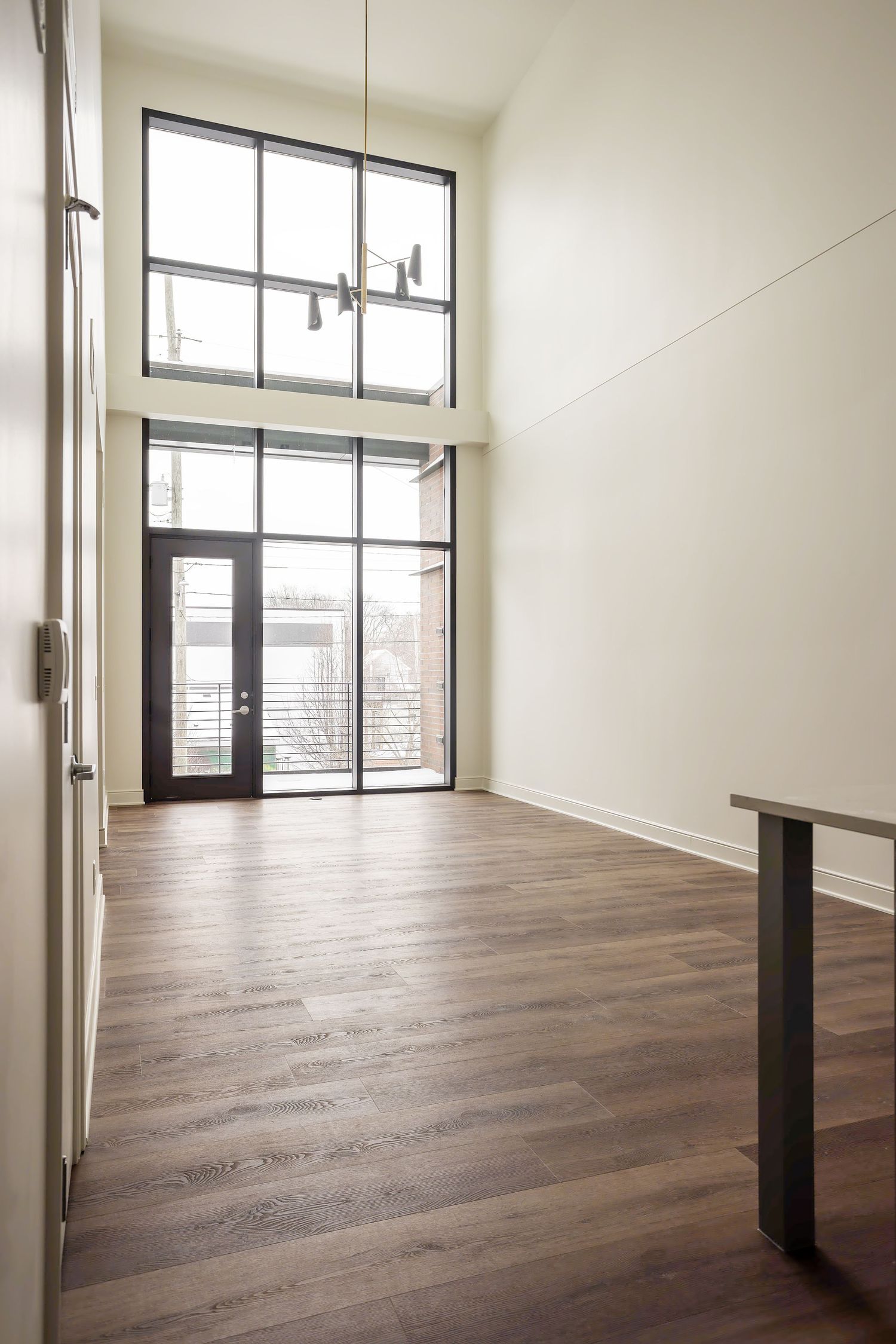 Modern apartment interior with tall floor-to-ceiling windows, hardwood flooring and minimalist design elements.
