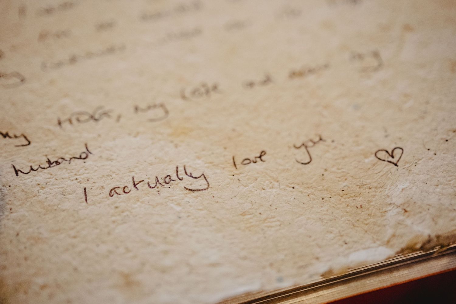 Handwritten message 'I actually love you' with a small heart doodle on aged paper.