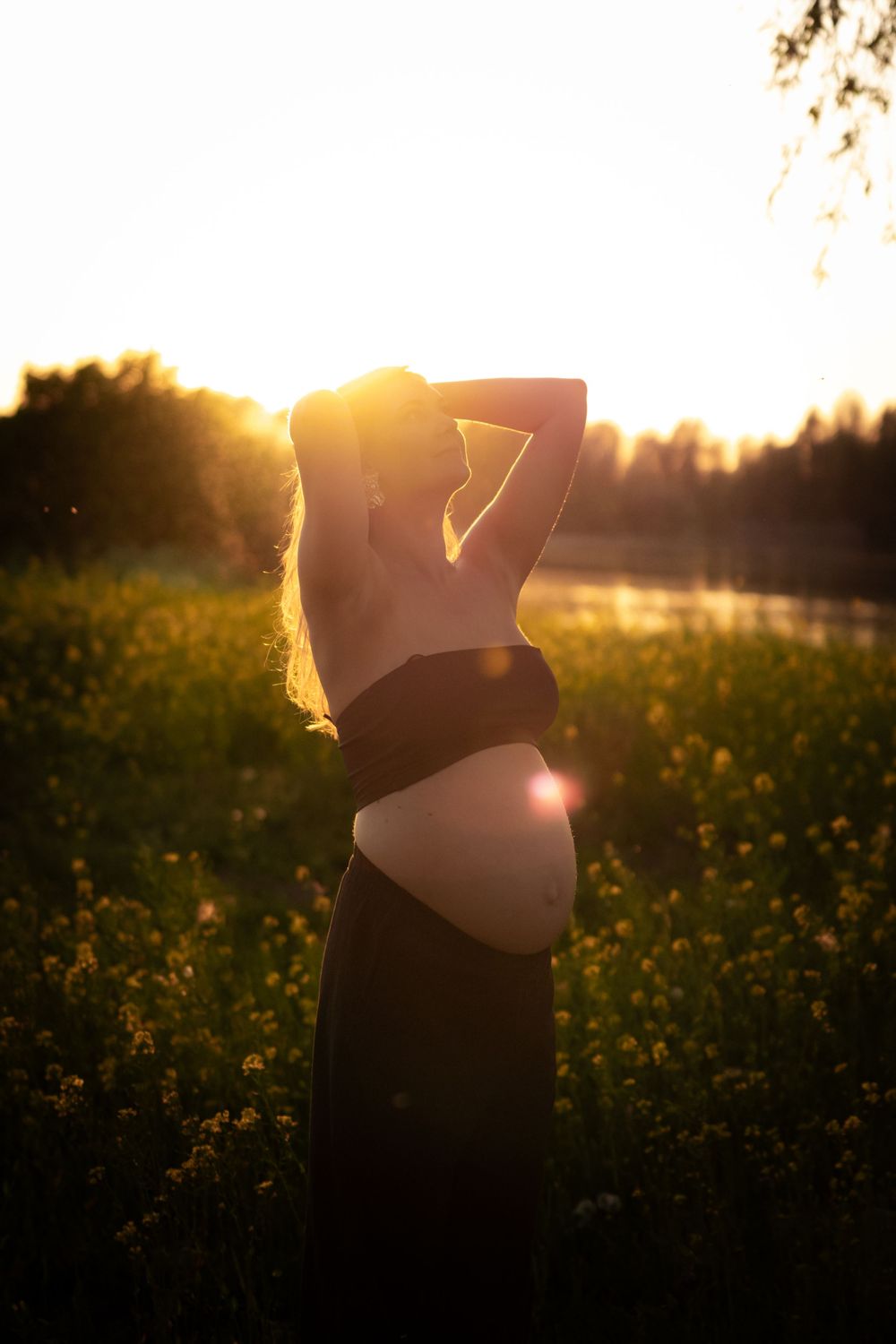 Silhouette of a figure stretching in a golden meadow at sunset, backlit by warm sunlight through flowers.