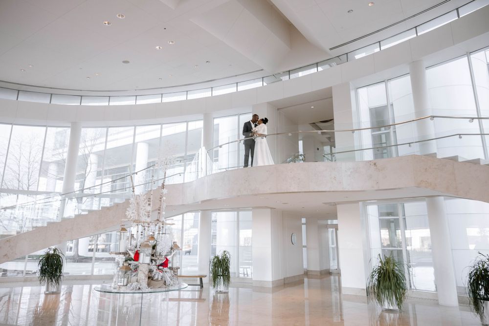 Contemporary white interior architecture showcases a wedding couple on an elevated curved balcony.