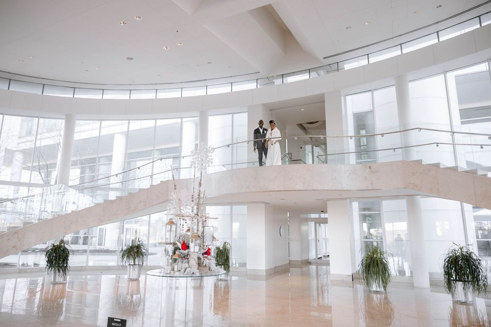 Modern architectural space with curved balconies and floor-to-ceiling windows featuring a wedding photo session.