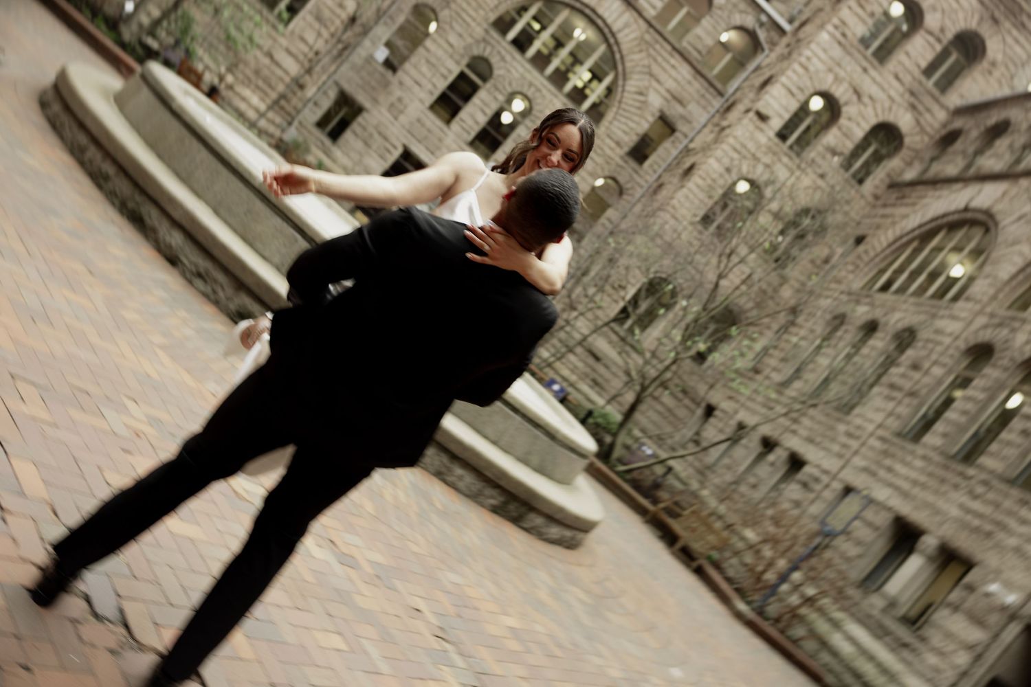 An angled view of a person in formal attire spinning against the backdrop of an ornate historic stone building.