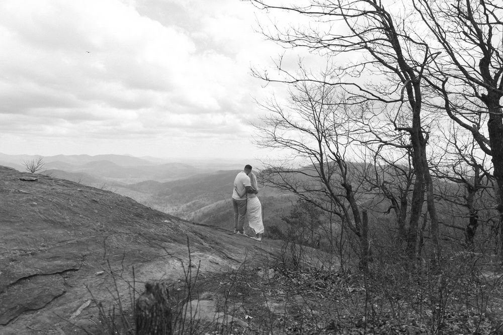 A newlywed couple embraces each other overlooking the blue ridge mountains on preachers rock.