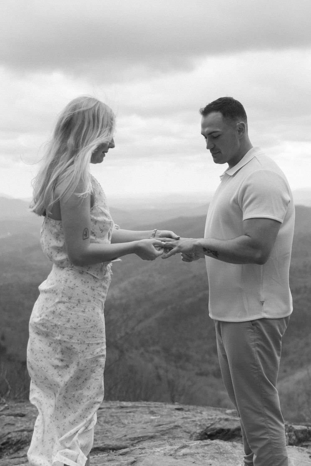 A couple exchanges rings during a mountaintop elopement against a dramatic cloudy sky and an appalachian mountain backdrop