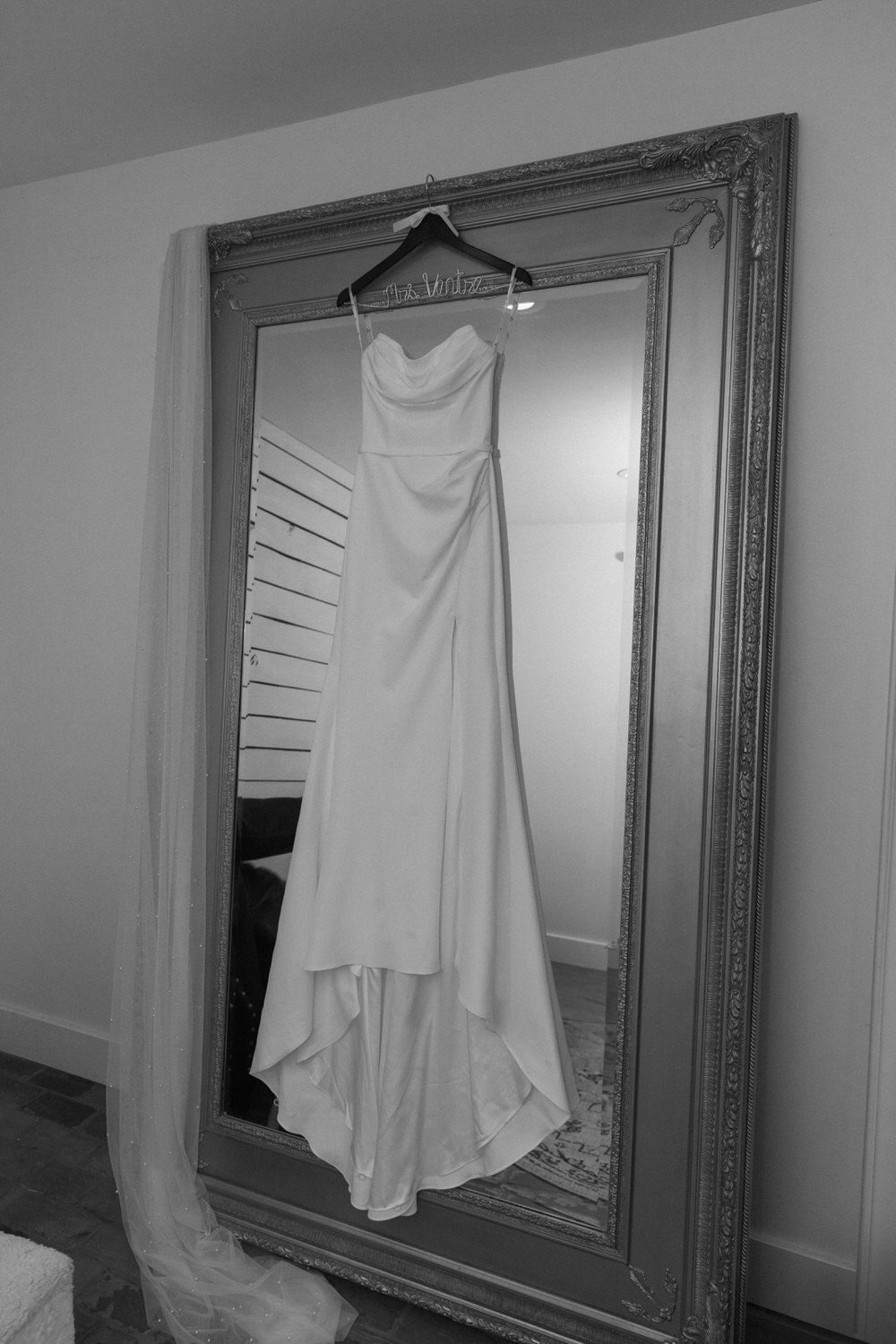 a bride's dress hanging on a large mirror while getting ready for her elopement in colorado