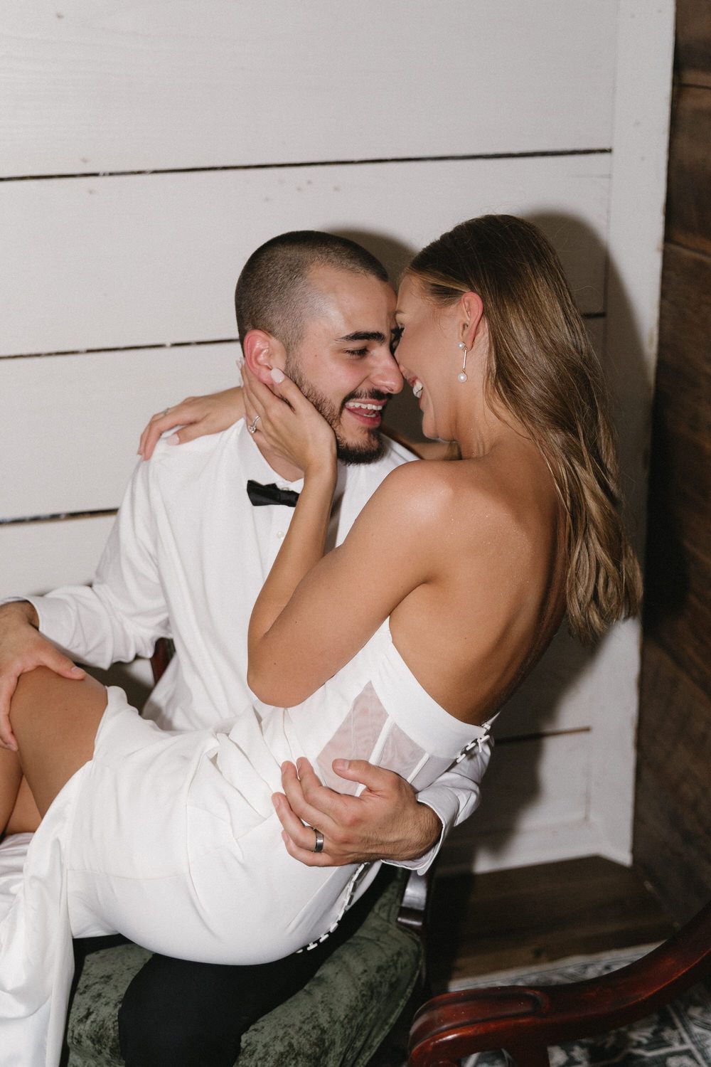 A romantic couple in wedding attire share an intimate moment while the groom holds his bride in their elopement airbnb