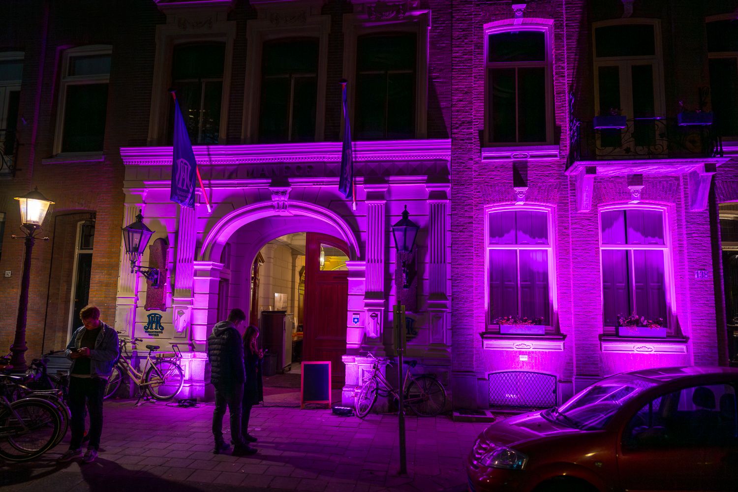 Historic building facade illuminated in vibrant purple lighting at night.