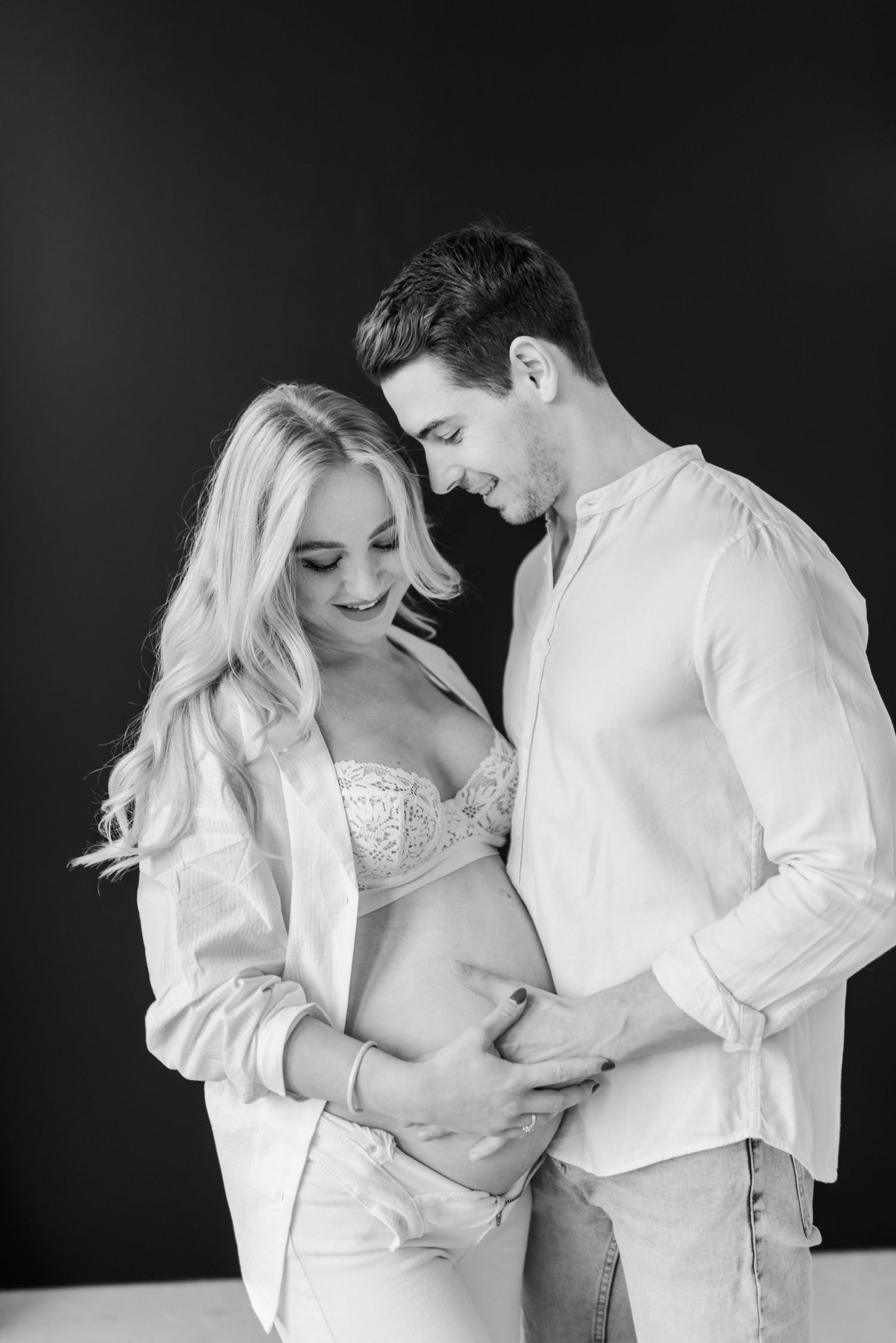 A romantic black and white photo series showing tender moments between a couple embracing in matching white outfits.