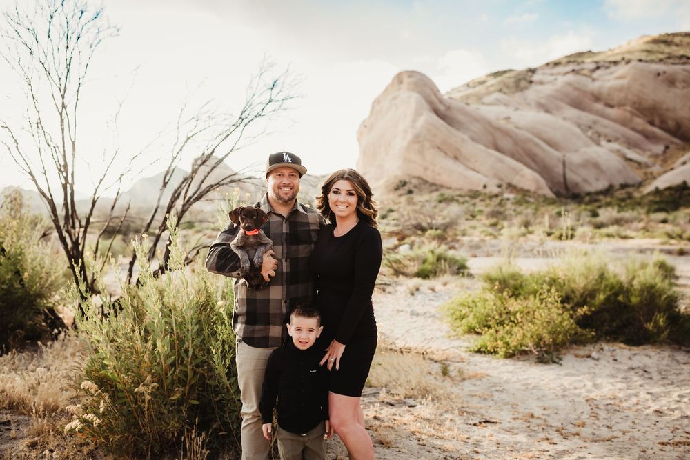 A family poses together against a scenic desert landscape with rocky mountains in the background.