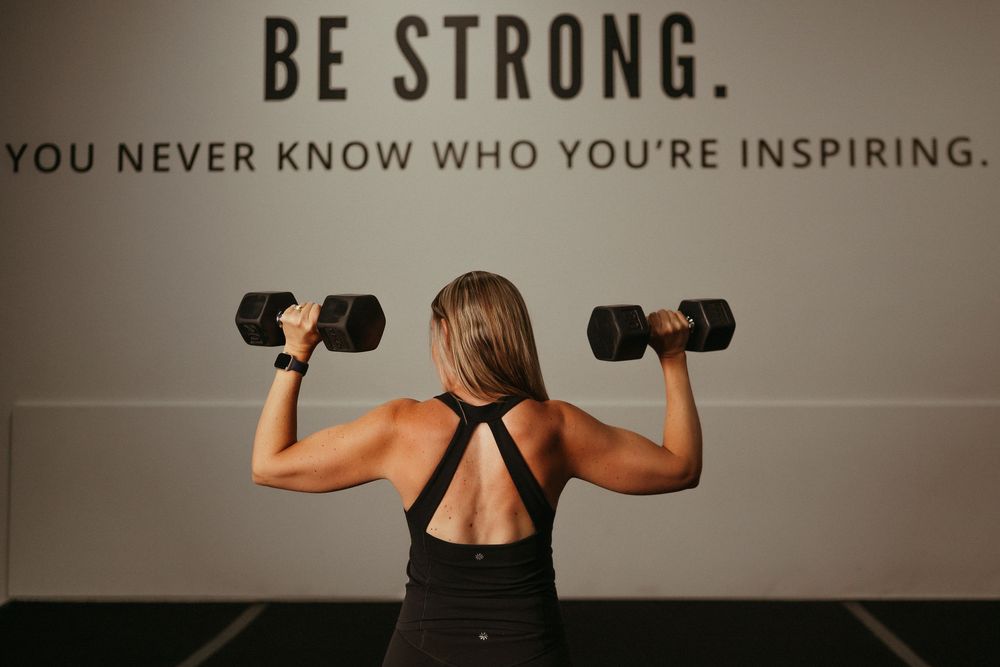 Fitness motivation collage showing multiple people exercising with weights and text saying Be Strong against a dark background.