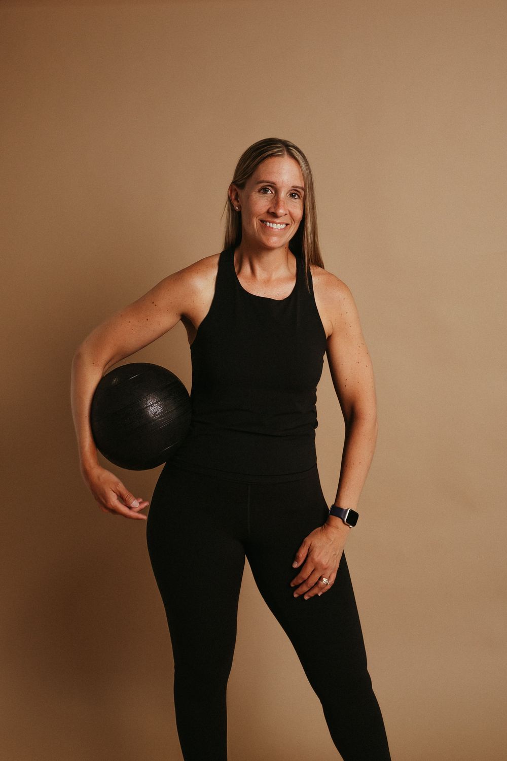 Athletic figure in black workout attire poses with basketball against neutral background in photo series.