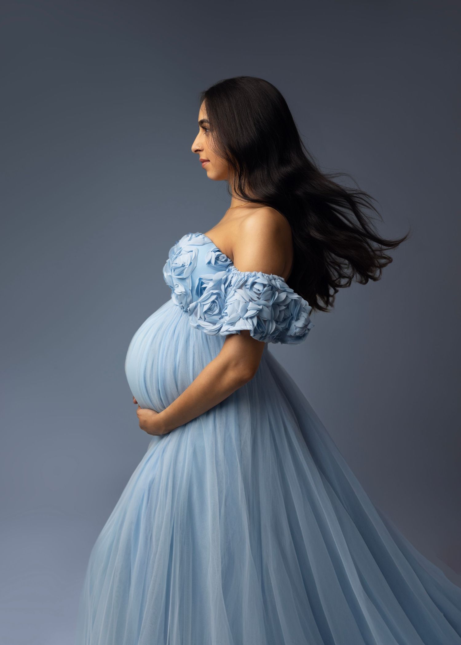 gorgeous mom in blue flowing tulle dress with floral accents. hair blows in the wind, maternity photos. Elizabeth Lang Photography Surrey.