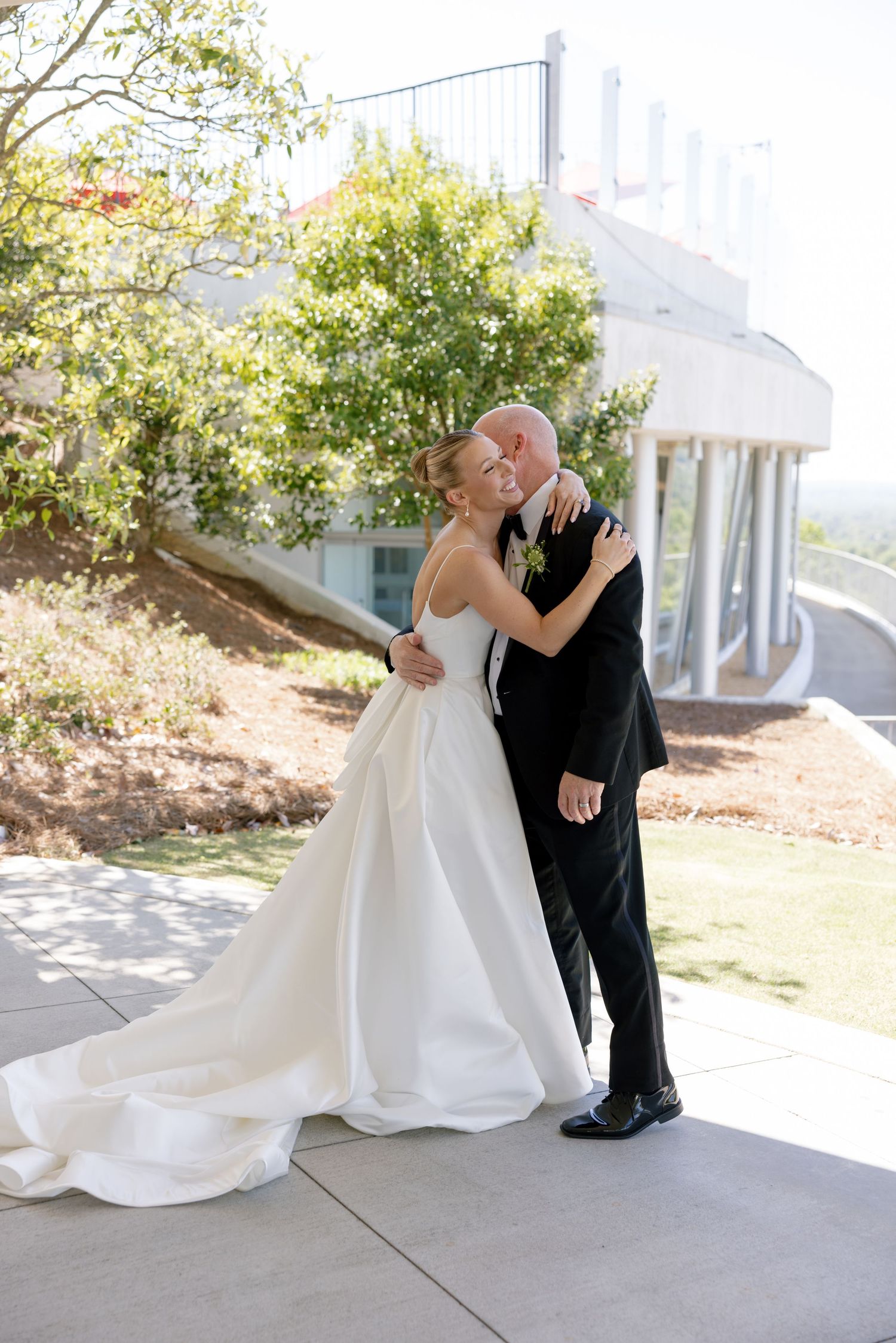 A couple shares a romantic moment on their wedding day on an outdoor patio surrounded by greenery.
