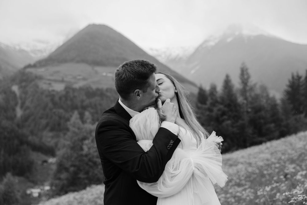 A couple shares a romantic kiss against a stunning mountain backdrop during their wedding photoshoot in snowy Aspen.
