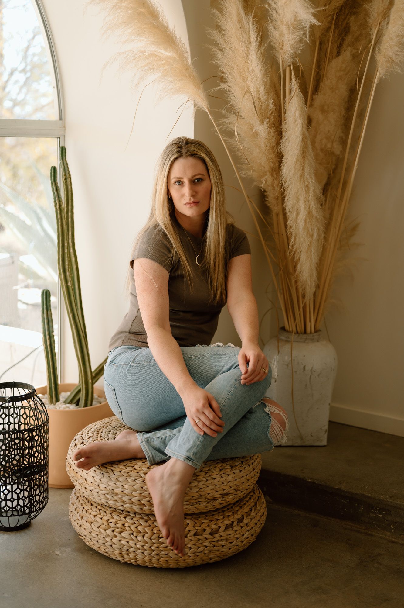 Tiffany Kelterer, Ventura County maternity Photographer, sitting on a boho pouf in a Joshua Tree airbnb