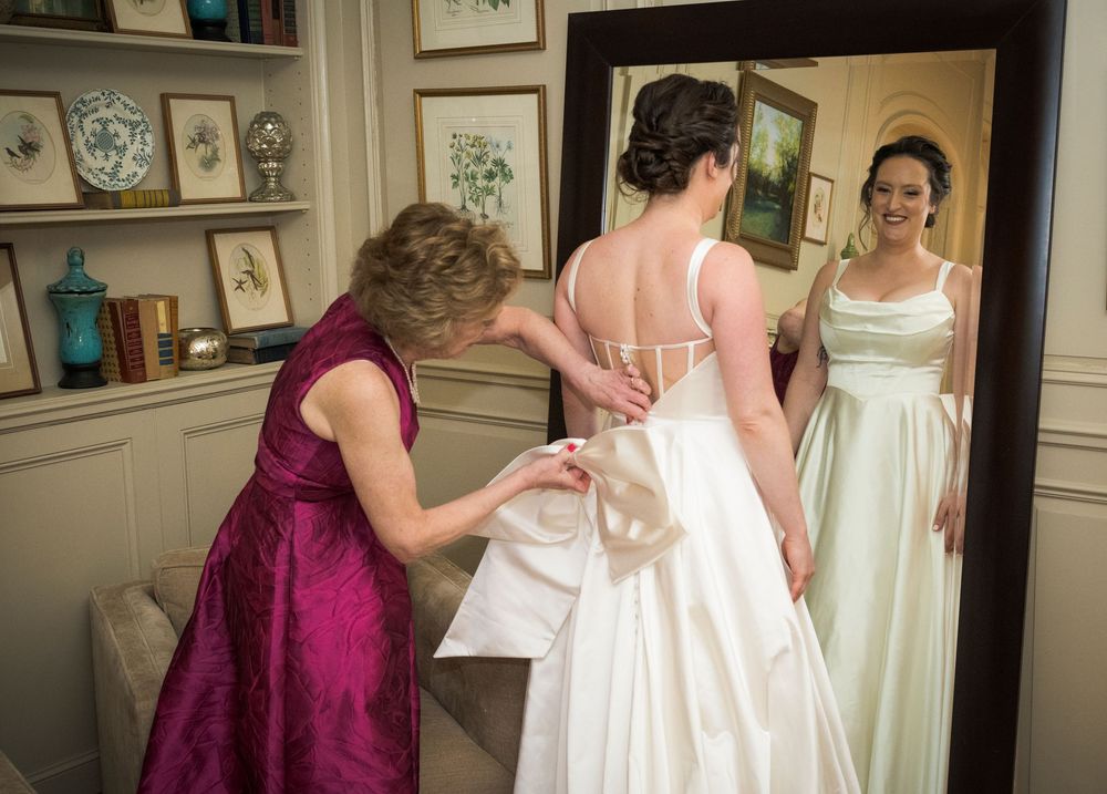 A heartwarming moment of wedding dress preparation in an elegant room with built-in shelving and decor.