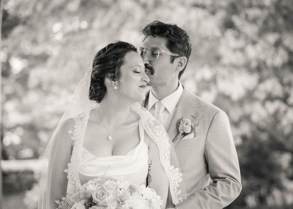 A romantic black and white portrait of a couple sharing an intimate moment on their wedding day.