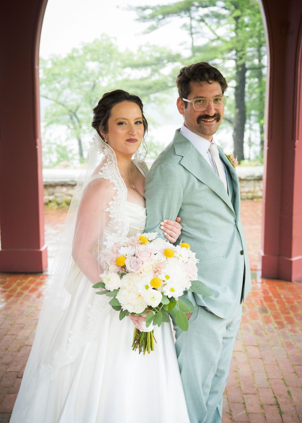 A couple poses together in a series of wedding photos on brick paving, with the bride holding yellow and white bouquet.