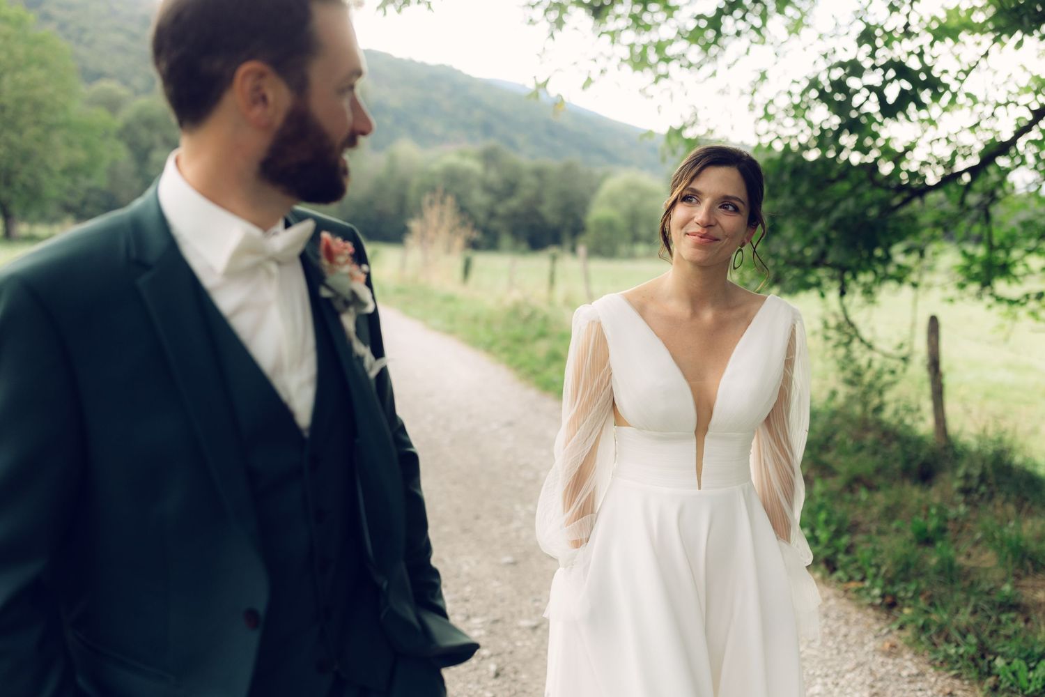 A bride and groom share a joyful moment on a country road surrounded by hills.