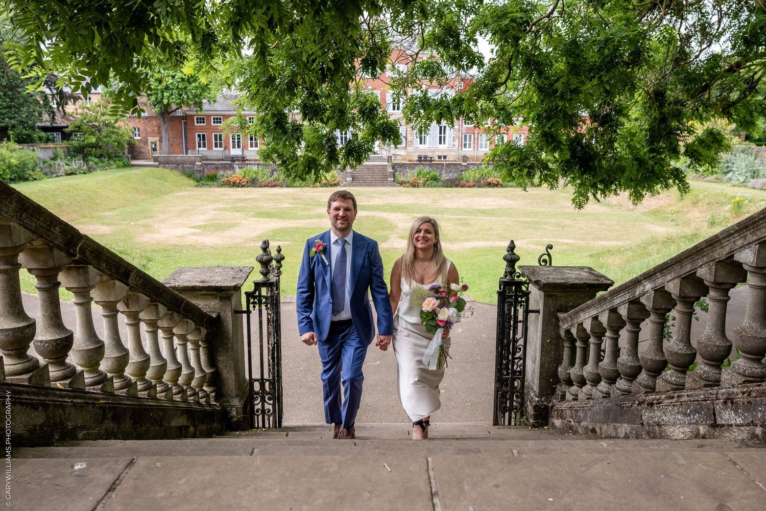 Wedding couple walking down old stone steps in a beautiful garden setting during their wedding celebration.