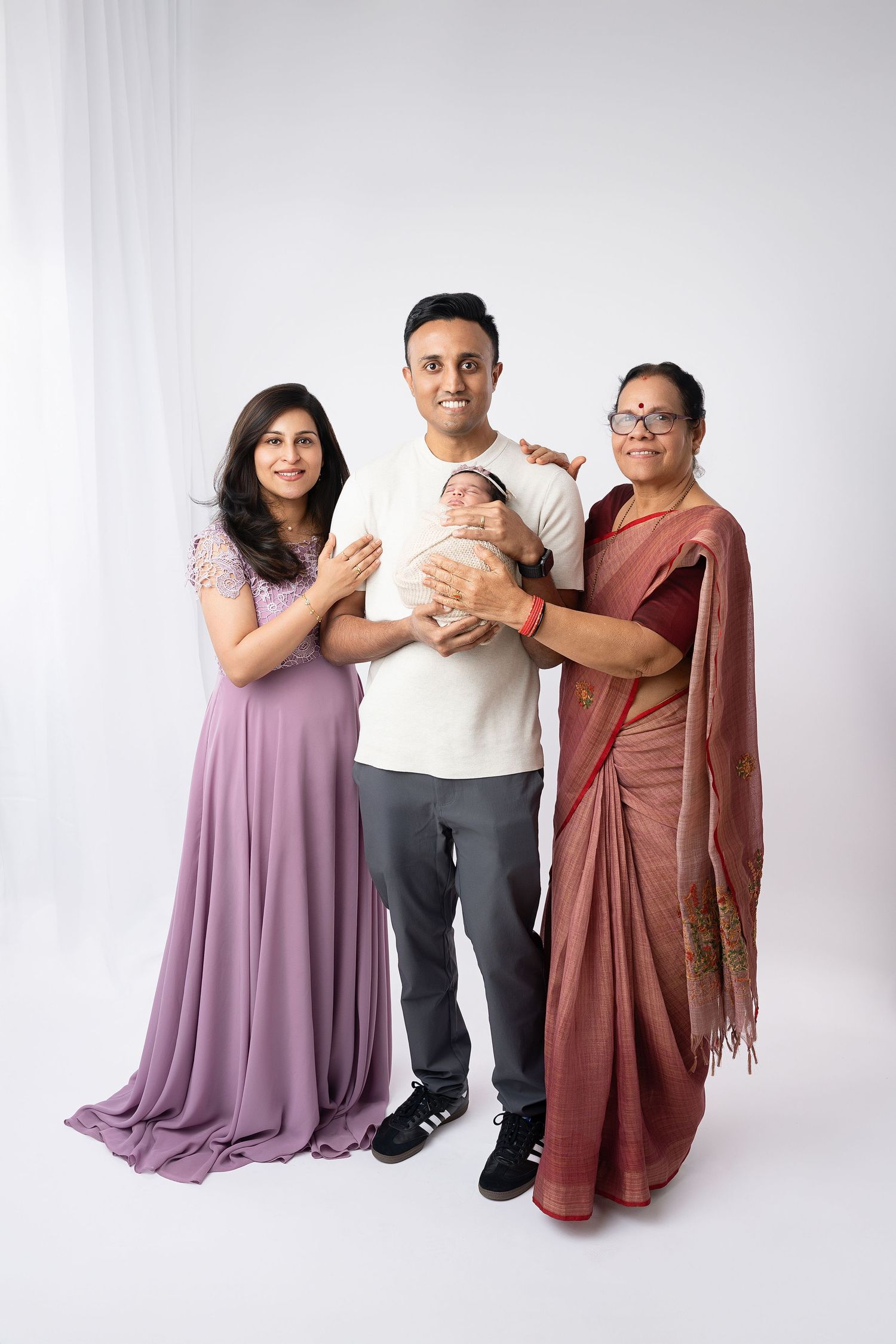 Family portrait with newborn baby against white studio background.