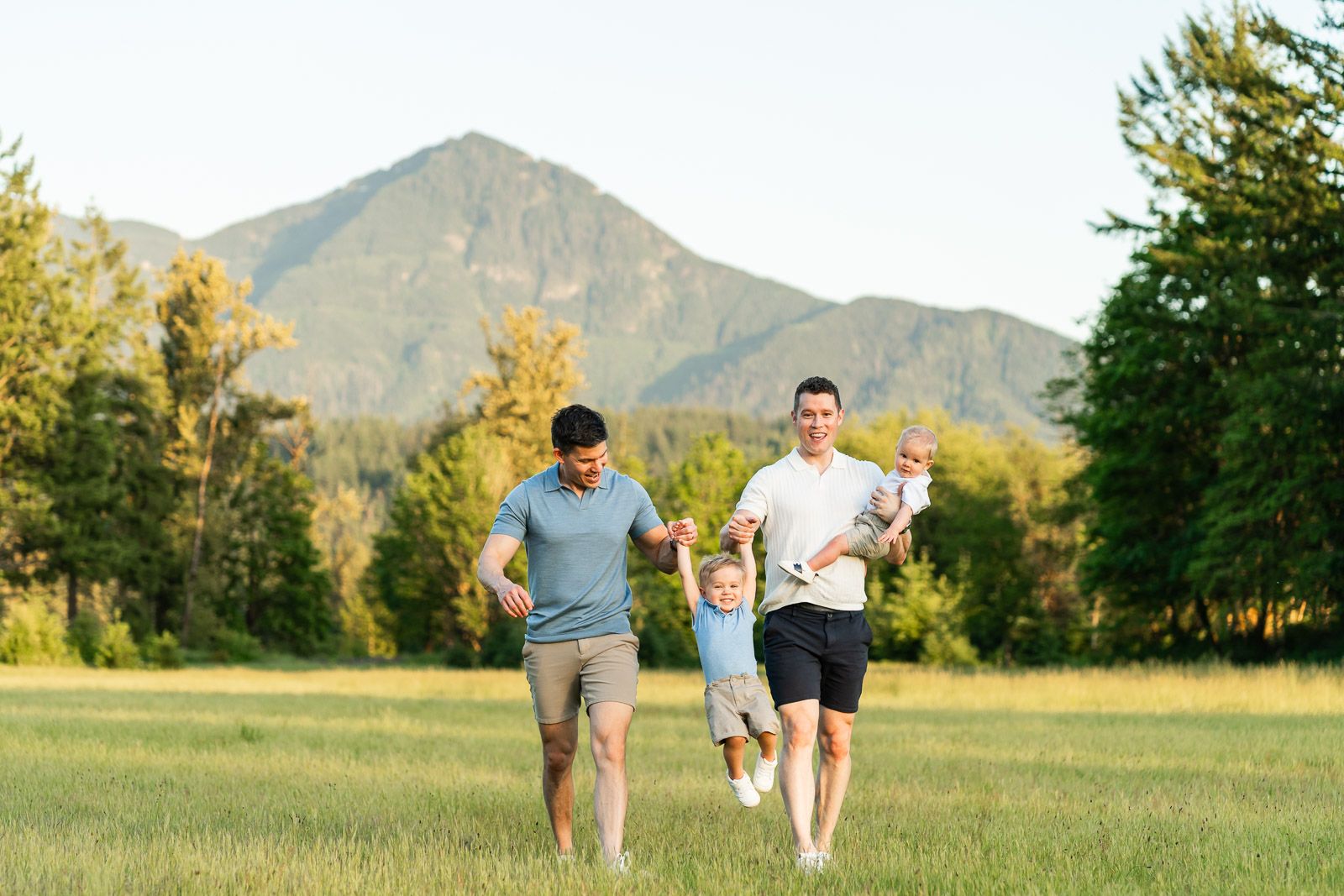 Dads swing their son in the air in front of Mt. Si backdrop.