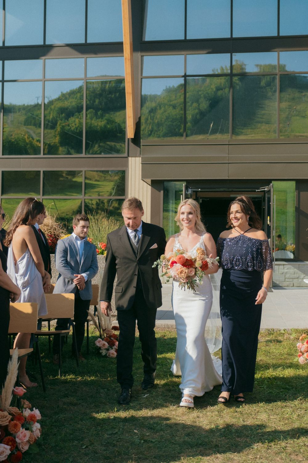 A bride walks down the aisle during an outdoor ceremony with mountain views.