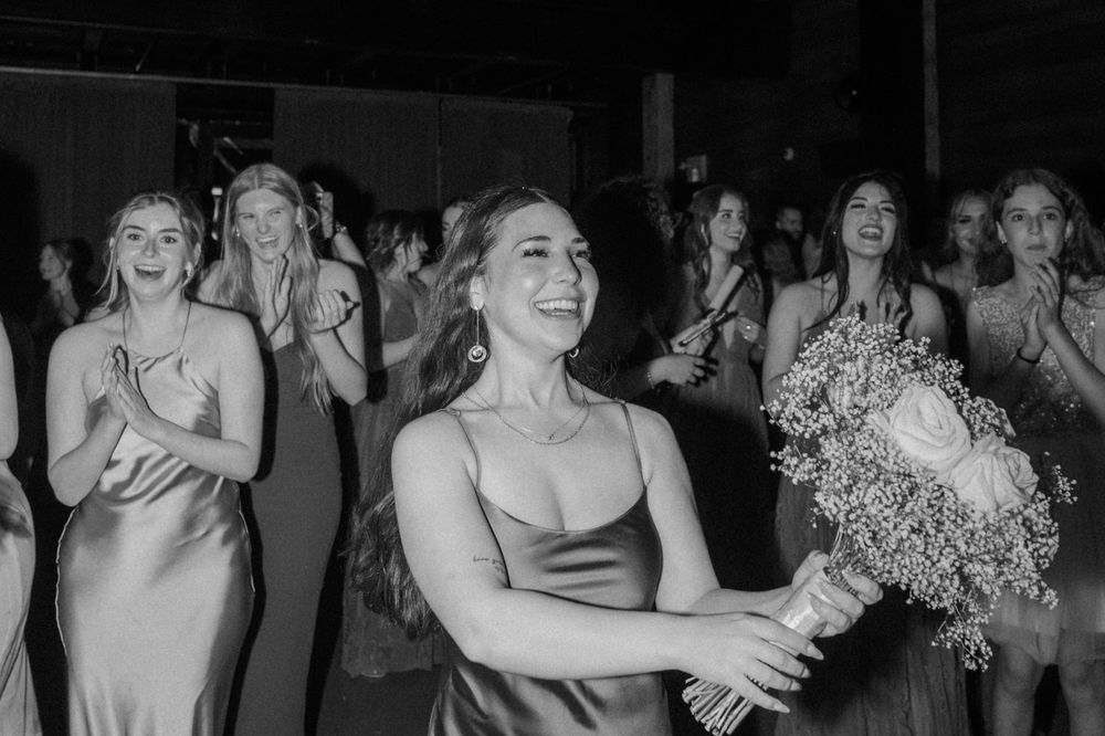 Candid black and white photo of wedding guests celebrating and laughing during reception.