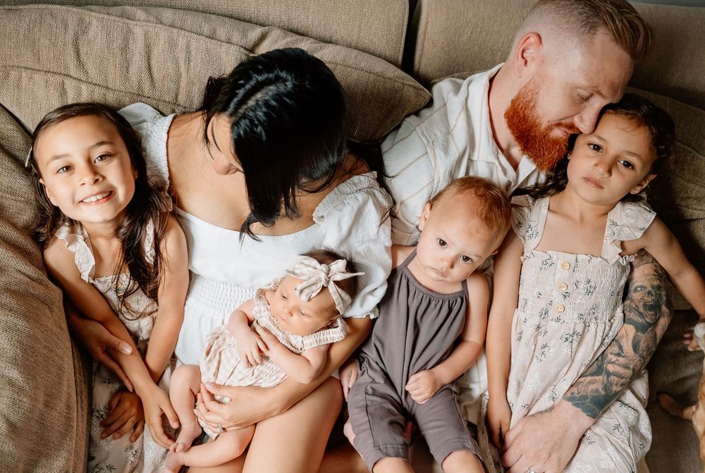A group lounges together on a cozy brown couch sharing intimate family moments and tender embraces.